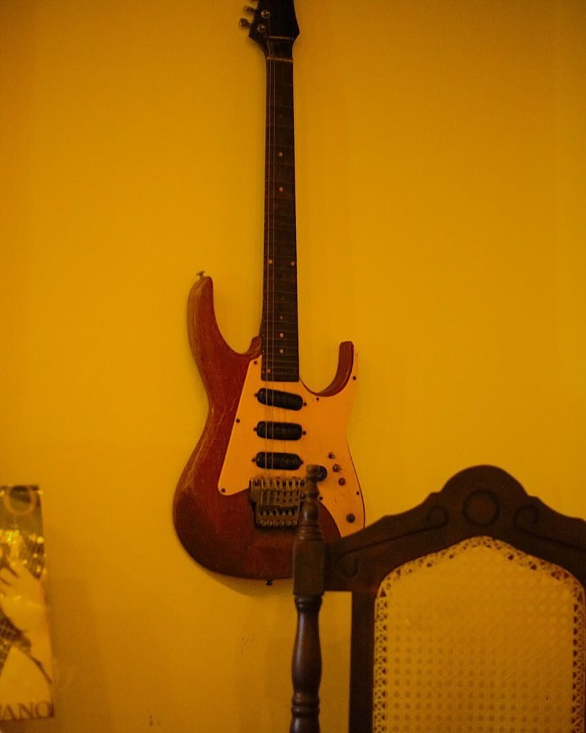 Guitarra pendurada na parede amarela do salão